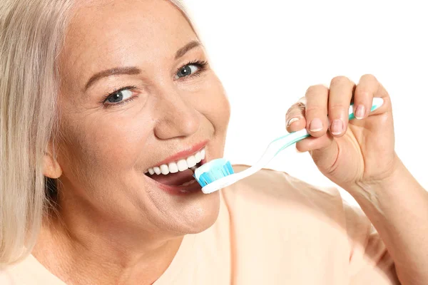 Reife Frau beim Zähneputzen auf weißem Hintergrund — Stockfoto