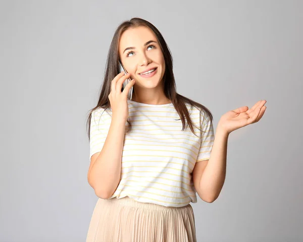 Portret van een mooie vrouw praten door mobiele telefoon op grijze achtergrond — Stockfoto