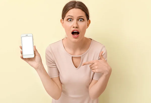 Shocked woman with mobile phone on color background — Stock Photo, Image