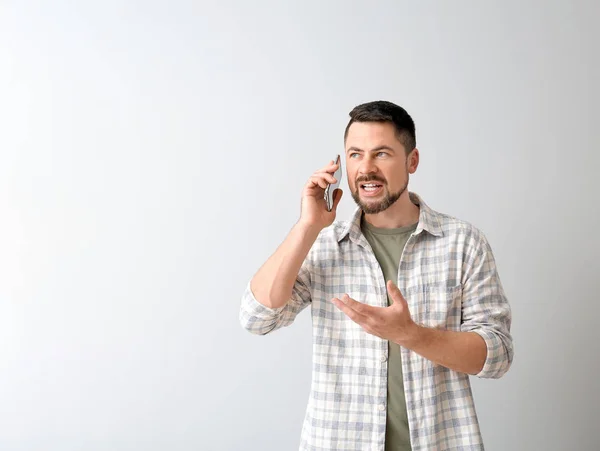 Hombre maduro hablando por teléfono sobre fondo claro — Foto de Stock