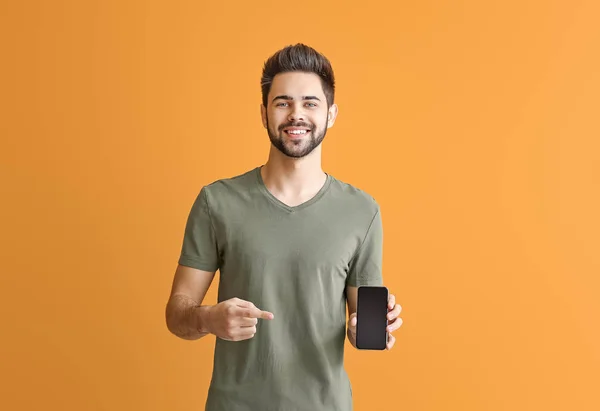 Happy young man with mobile phone on color background — Stock Photo, Image