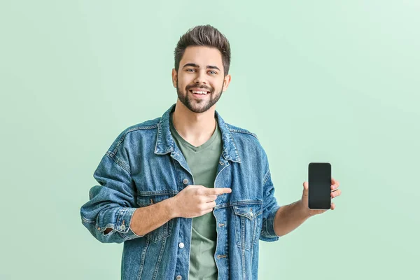 Happy young man with mobile phone on color background — Stock Photo, Image