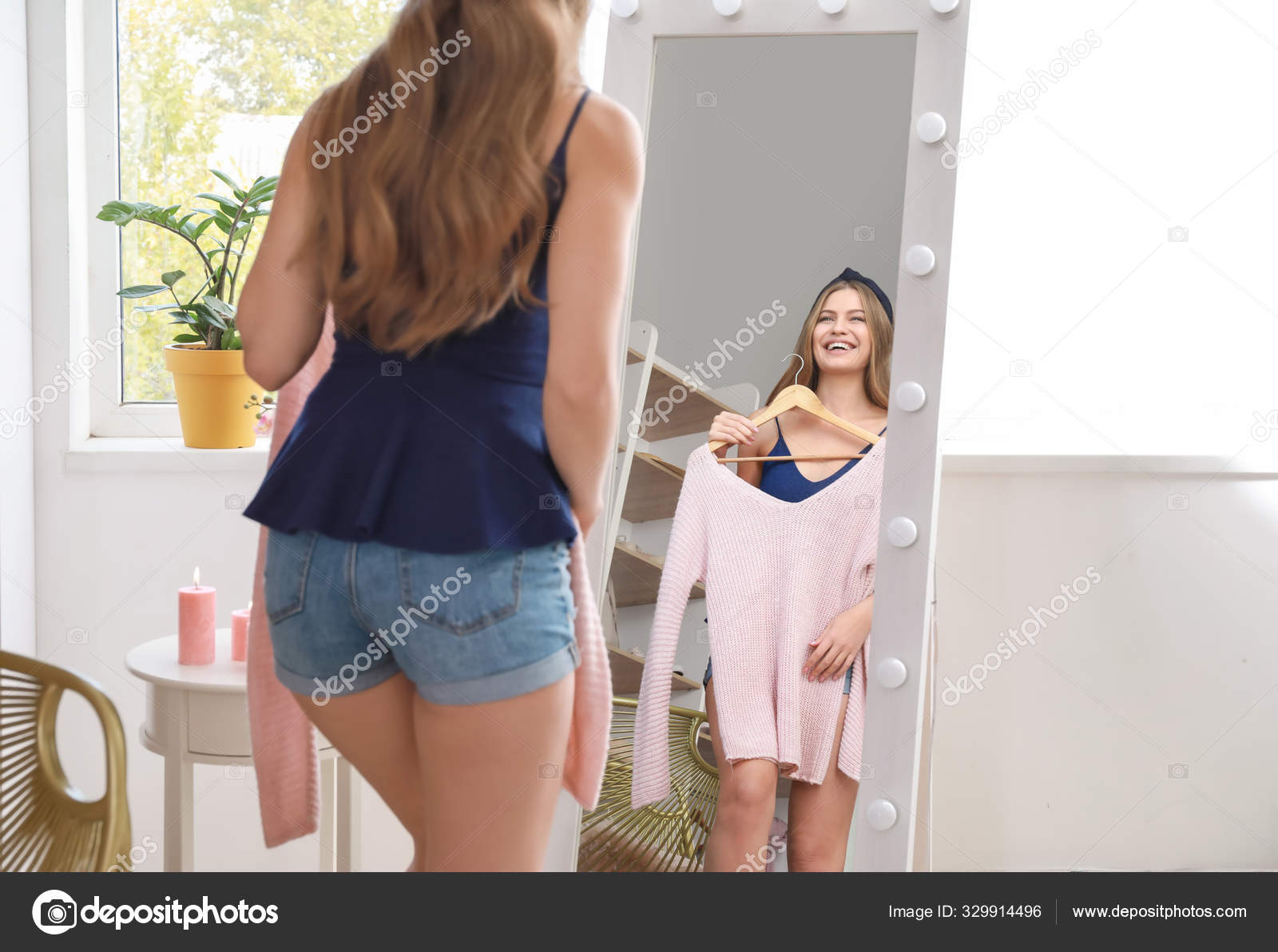 Beautiful Young Woman Choosing Clothes In Front Of Mirror Stock