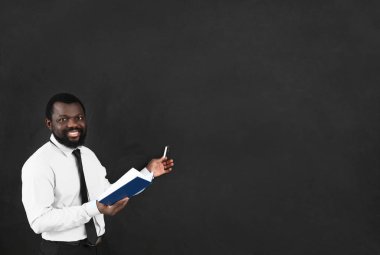 Sınıfta tahtaya yakın bir kitabı olan Afro-Amerikan bir öğretmen.