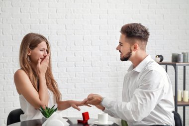 Genç adam evlilik teklifinden sonra nişanlısının parmağına yüzük takıyor.