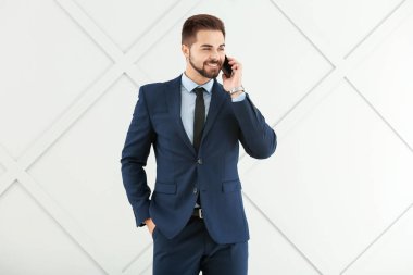 Gri arka planda cep telefonuyla konuşan yakışıklı iş adamının portresi