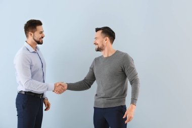 Renkli arka planda el sıkışan genç iş adamlarının portresi