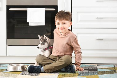 Şirin köpekli küçük bir çocuk ve mutfakta yemek için kase.