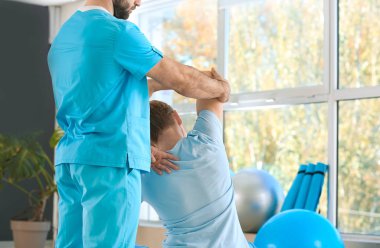 Rehabilitasyon merkezinde erkek hastayla çalışan fizyoterapist.