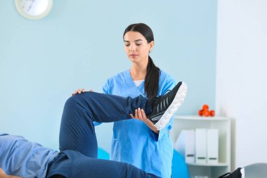 Rehabilitasyon merkezinde erkek hastayla çalışan fizyoterapist.