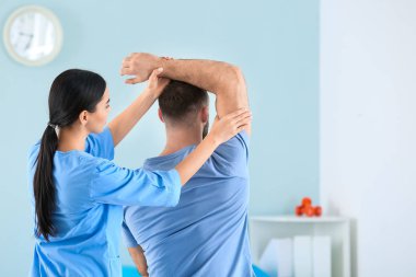 Rehabilitasyon merkezinde erkek hastayla çalışan fizyoterapist.