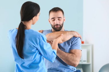 Rehabilitasyon merkezinde erkek hastayla çalışan fizyoterapist.