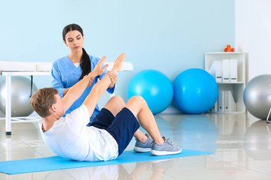 Rehabilitasyon merkezinde erkek hastayla çalışan fizyoterapist.