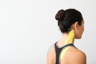 Boynu hafif arkaplana yapıştırılmış, fizyolojik bantlı sportif bir kadın.