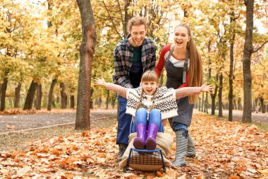 Sonbahar yapraklarını temizlerken aile eğleniyor.