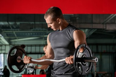 Spor salonunda halterli kaslı adam eğitimi.