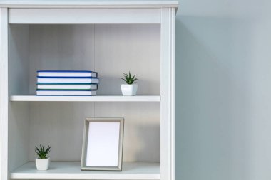 Beyaz duvarın yanında dekorlu raf ünitesi