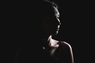 Karanlık arka planda güzel genç bir kadının silueti.