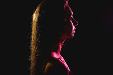 Koyu arkaplanda güzel bir genç kadının tonlanmış silueti.