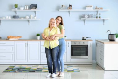 Olgun bir kadın ve yetişkin kızı mutfakta birlikte.