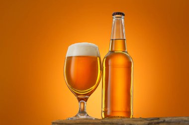 Masadaki bira şişesi ve bardağı renk arkaplanına karşı.