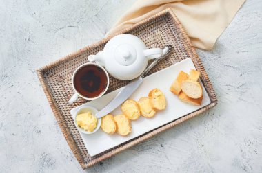 Beyaz arka planda lezzetli ekmek, tereyağı ve çay tepsisi