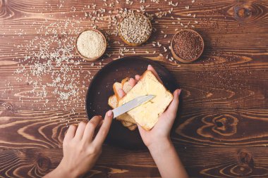Lezzetli tereyağını ekmeğin üstüne döken bir kadın.