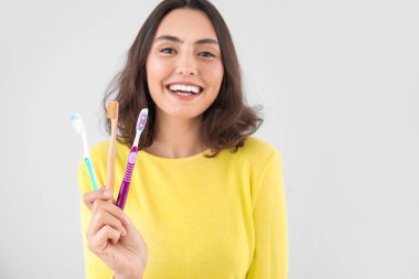 Farklı arka planda farklı diş fırçaları olan güzel genç bir kadın.