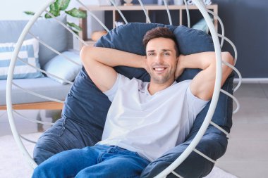 Evdeki koltukta oturan yakışıklı adam.