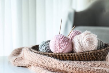 Evdeki masada örgü ipliği ve iğnelerle dolu sepet.