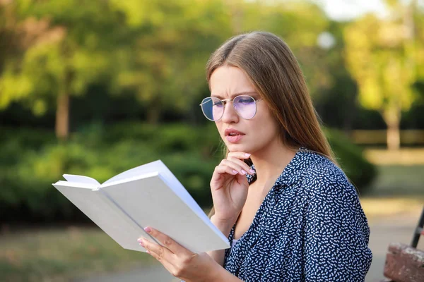 Vacker ung kvinna läser bok i parken — Stockfoto