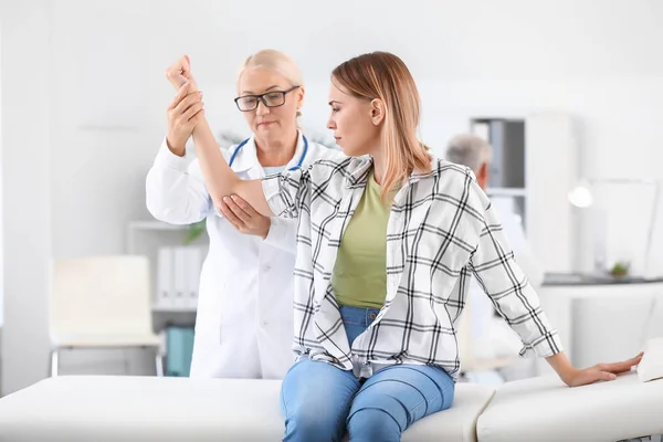 Ärztin untersucht junge Frau mit Gelenkschmerzen in Klinik — Stockfoto