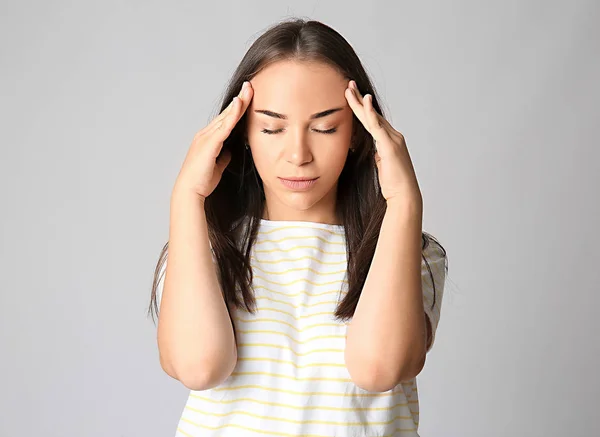 Portrait of woman suffering from head ache on grey background — Stock Photo, Image