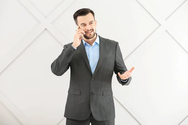 Retrato de hombre de negocios guapo hablando por teléfono móvil sobre fondo gris —  Fotos de Stock