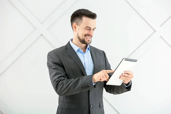Portret van een knappe zakenman met tablet computer op grijze achtergrond — Stockfoto