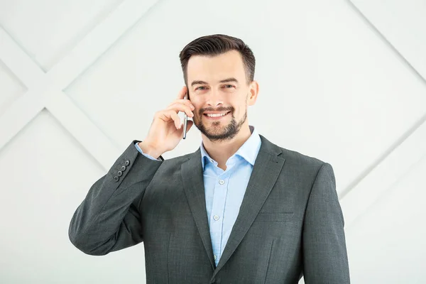 Retrato de hombre de negocios guapo hablando por teléfono móvil sobre fondo gris —  Fotos de Stock