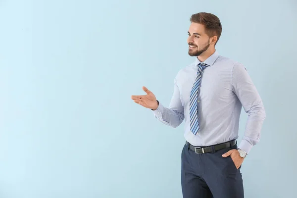 Retrato de jovem empresário mostrando algo sobre fundo de cor — Fotografia de Stock