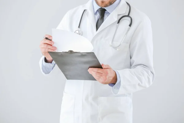 Médico masculino con portapapeles sobre fondo claro —  Fotos de Stock