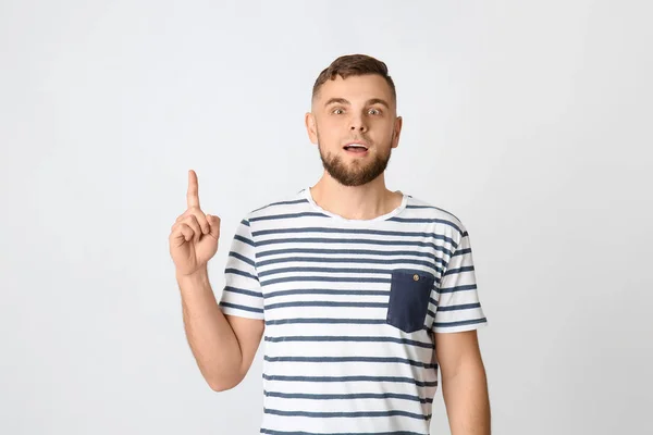 Emotional young man pointing at something on grey background — Stock Photo, Image