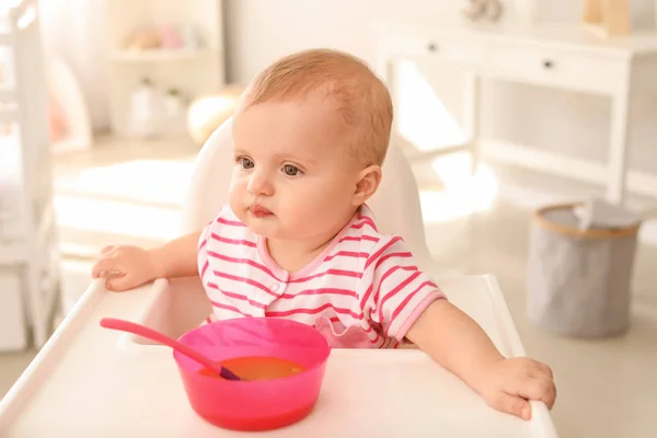 Portrait of cute little baby eating tasty food in kitchen — Stock Photo, Image