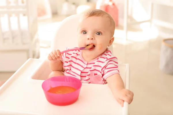 Retrato de bebé lindo comiendo comida sabrosa en la cocina — Foto de Stock