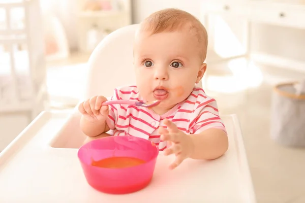 Retrato de bebé lindo comiendo comida sabrosa en la cocina — Foto de Stock