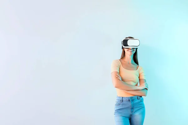 Junge Frau mit Virtual-Reality-Brille auf hellem Hintergrund — Stockfoto
