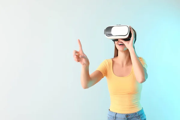 Young woman with virtual reality glasses on light background — Stock Photo, Image