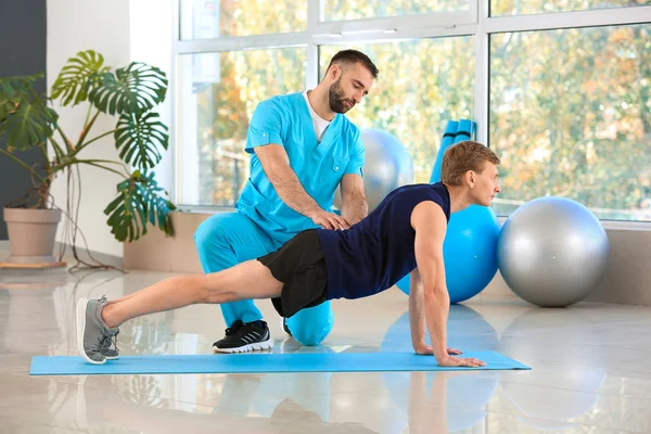 Fisioterapeuta trabajando con paciente masculino en centro de rehabilitación —  Fotos de Stock