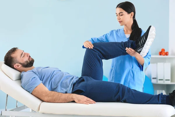 Fisioterapeuta trabajando con paciente masculino en centro de rehabilitación — Foto de Stock