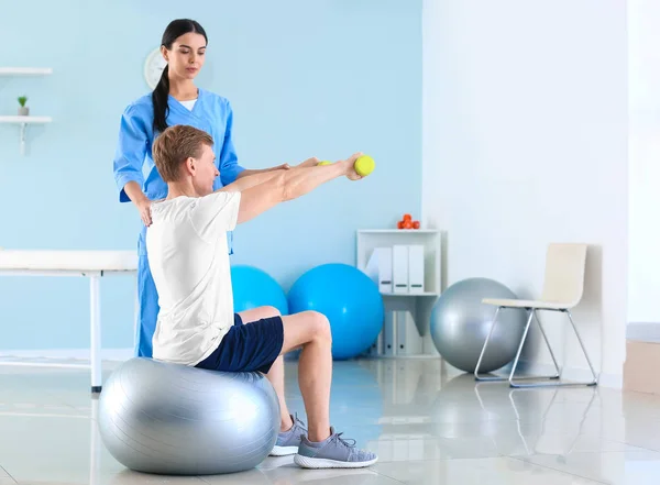Fisioterapeuta trabajando con paciente masculino en centro de rehabilitación —  Fotos de Stock