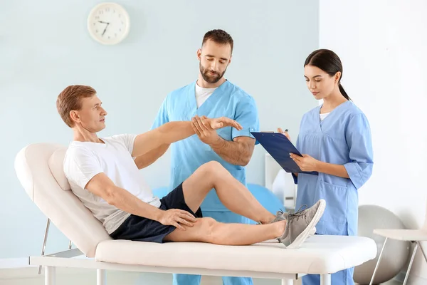 Physiotherapists working with male patient in rehabilitation center — Stock Photo, Image