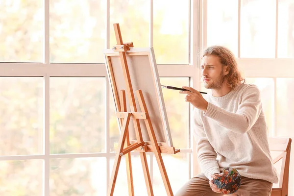 Young male artist painting in studio