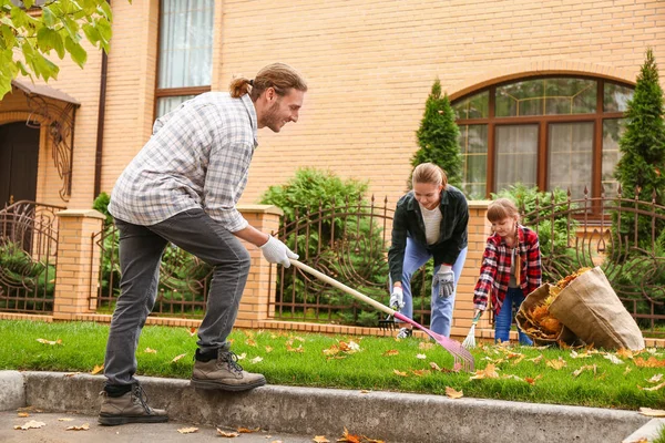 Família limpando folhas de outono ao ar livre — Fotografia de Stock